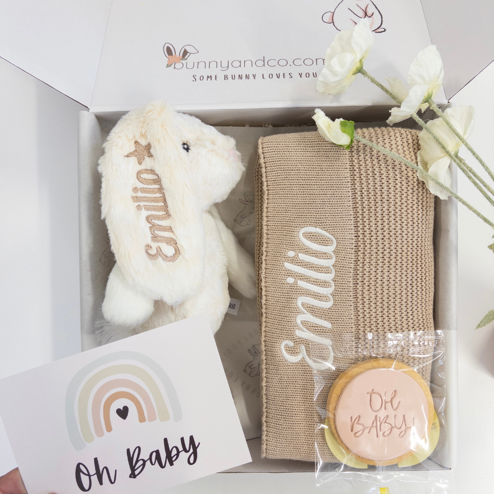 Newborn baby boy or girl infant Gift hamper with personalised bunny toy, personalised baby blanket, and cookie in a box, featuring 'Emilio' on items.
