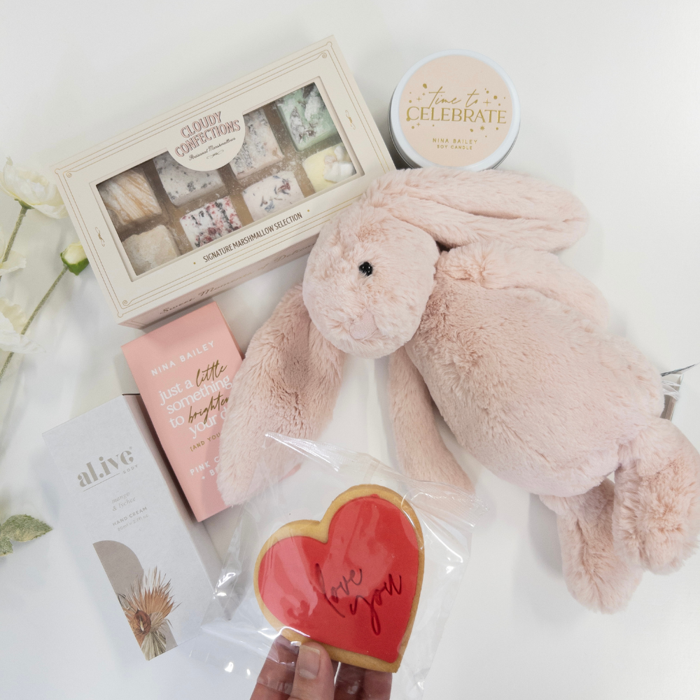 Jellycat Bunny Mum and Baby Gift hamper featuring a Blush Pink Bashful Jellycat Bunny, heart-shaped cookie, and gift box on a white surface