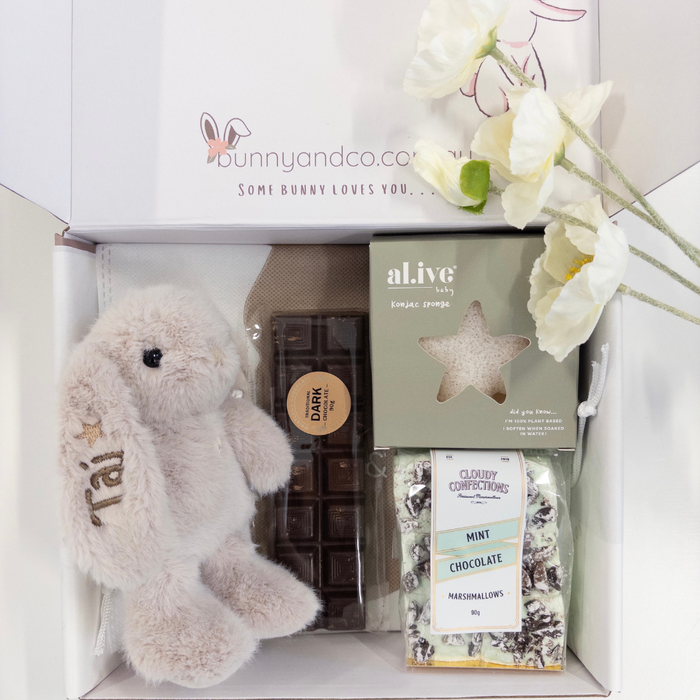 Gift box with a personalised plush toy, chocolate bar, and other items for new Mum, featuring the brand 'bunnyandco'.