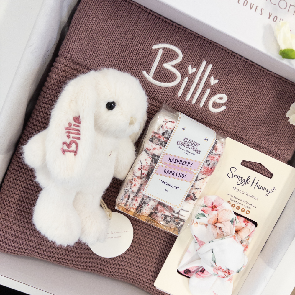 White teddy bear bunny personalised custom name 'Billie' on a plum purple blanket with two products in the foreground. Gift Hamper for new baby Australia