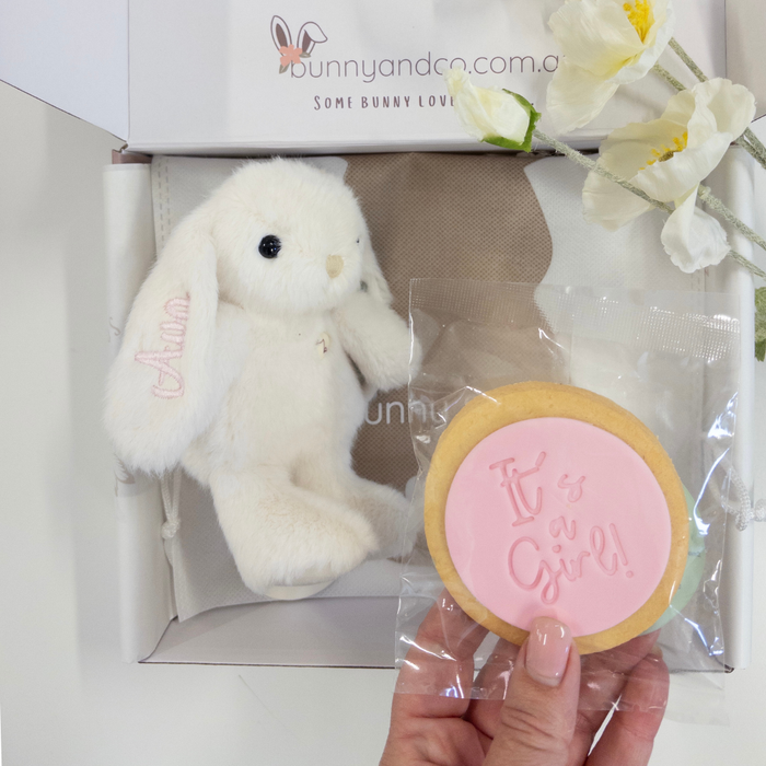 White bunny toy and pink 'It's a Girl!' cookie in a box with bunnyandco.com branding.