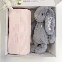 Pink blanket and gray stuffed bunny in a box with 'Emilia' and 'Sofia' embroidered.