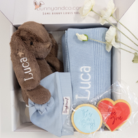 Gift set with a brown plush personalised bunny, blue baby blanket with custom name, and cookies in a box.