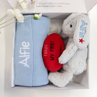 Baby gift set with blue blanket, red heart, and gray bunny toy in a box.
