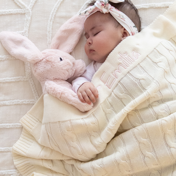 Baby sleeping with a pink Jellycat bunny toy in Blush Pink and a personalised cream cable knit blanket for baby girl