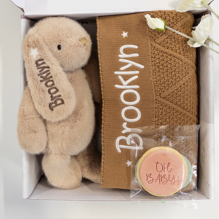 Gift set with personalised plush bunny rabbit toy, personalised brown diamond knit baby blanket, and treat for new mum in gift box.