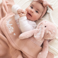 Baby lying on a pink personalised baby blanket with a plush bunny toy, engraved with name on blanket and bunny baby gift australia