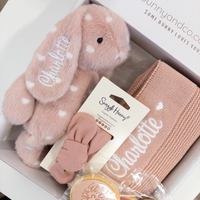 Pink bunny toy, knitted blanket, and pacifier with 'Charlotte' on packaging in a box.